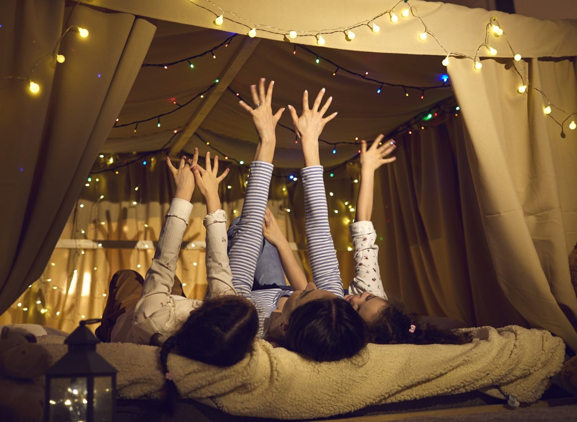 Børn der overnatter i telt indenfor med lyskæder